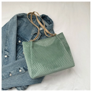 Detail of green tote bag with woven grid texture on denim and white fabric background
