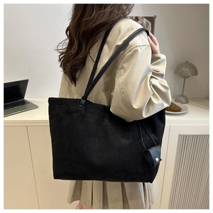 Close-up of a large black suede tote bag with a matching mini pouch on a long strap