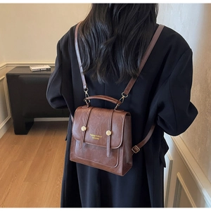 Detailed close-up of the vintage brown faux leather backpack with gold buckle and logo
