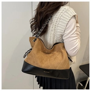 Detail of vintage quilted tote bag with brown suede, black leather base and chain strap