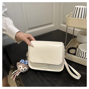 Détail du sac bandoulière blanc crème avec gaufrage animal et breloque ours peluche