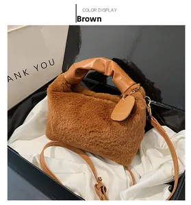 Détail du sac en peluche marron avec poignée en cuir plissée et étiquette dans un coffret