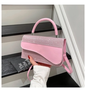 Close-up of pink leather handbag featuring sparkling rhinestone flap and silver hardware