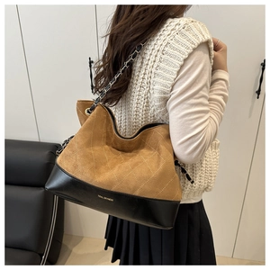 Detail of a large quilted chain tote bag with brown suede and black leather stitching