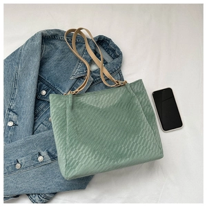 Light green tote bag with diamond pattern showing capacity next to a smartphone