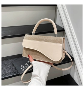 Detail of beige saddle handbag with shimmering rhinestones and leather handle