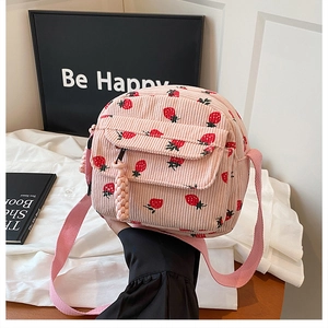 Detail view of pink corduroy strawberry crossbody bag with front pocket and zipper