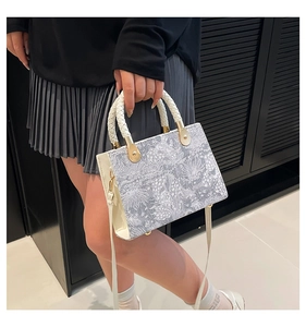 Detail of the intricate gray floral jacquard pattern and gold hardware on the handbag