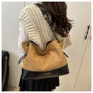 Detail of vintage quilted chain tote bag in tan suede with black leather trim worn by model