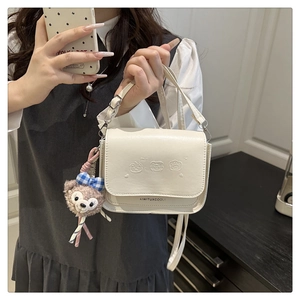 Détail du sac à bandoulière carré crème avec gaufrage et accessoire pendentif ourson