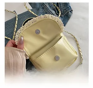 Detail of yellow mini bag with lace trim, magnetic buckle and high-quality hardware