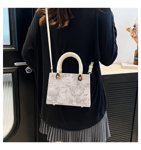 Detailed view of a white lace-textured rectangular handbag with woven handles on a model