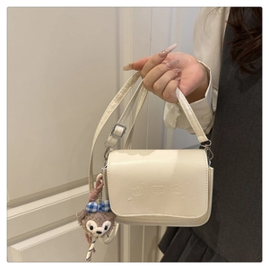 Détail d'un sac bandoulière en cuir PU blanc crème avec relief et charme en peluche