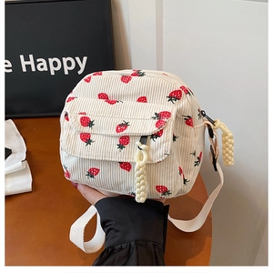 Detail of corduroy mini crossbody bag with red strawberry pattern and woven zipper pull