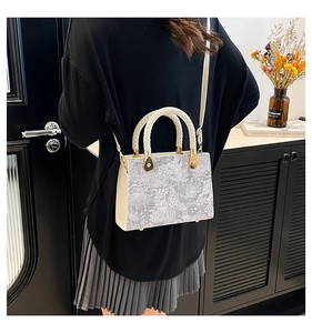 Detail of elegant beige crossbody bag with silver lace flower patterns on model's back