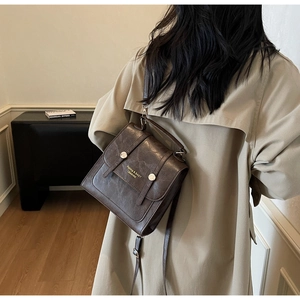Detail of dark brown retro square bag with textured finish and silver metal buckle