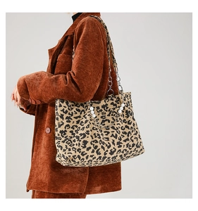 Detail of leopard print tote bag featuring pearl and metal chain strap on fabric