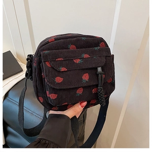 Detail of black corduroy crossbody bag featuring sweet red strawberry embroidery patterns