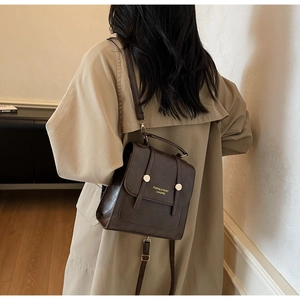 Detail of vintage dark brown faux leather backpack with gold buckles and dual straps