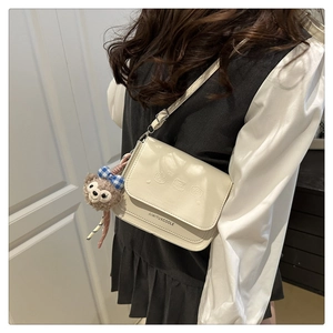 Détail du sac bandoulière blanc crème avec gaufrage d'ours et charm en peluche