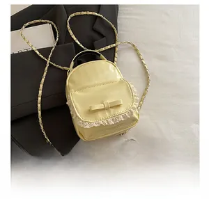 Mini yellow PU backpack with lace trim and bow detail shown next to a smartphone