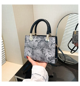 Detail of woven fabric tote with black braided handle and golden metallic hardware