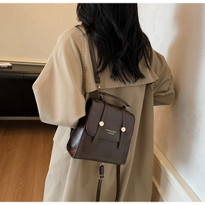Detail of dark brown vintage PU leather backpack with metallic ring on a model
