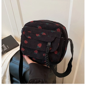 Close-up of black corduroy crossbody bag with cute red strawberry patterns and front flap