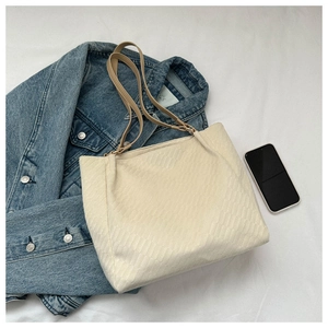 Detail of cream tote bag featuring quilted texture and stylish contrast leather straps