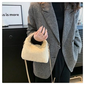 Vue détaillée du sac à main en peluche crème avec poignée en cuir et boucles en métal