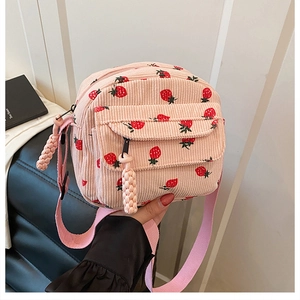 Detailed macro view of pink corduroy crossbody bag featuring a cute strawberry pattern