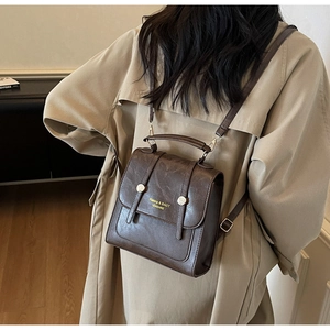 Detail of a vintage dark brown PU leather backpack with gold metal buckle and handle