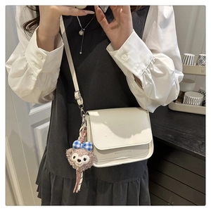 Détail d'un sac bandoulière blanc gaufré avec un charmant lapin en peluche et rabat