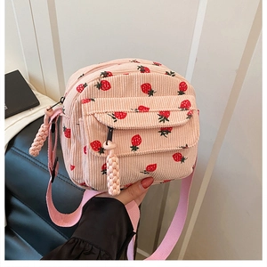 Detail of pink corduroy crossbody bag with red strawberry print and zipper close