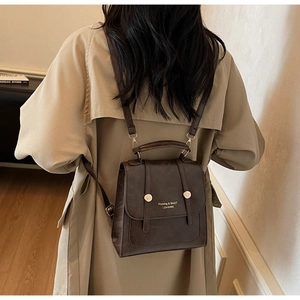 Detail of dark brown vintage backpack with gold buckle and adjustable strap on a model