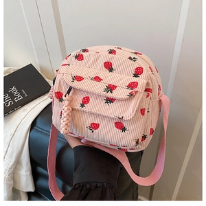 Detail of pink corduroy crossbody bag featuring strawberry pattern and soft pompom zipper