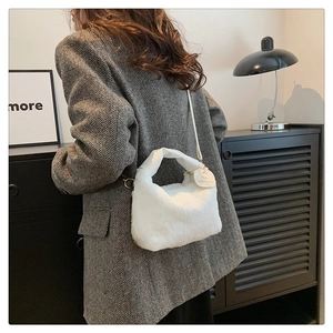 Vue détaillée d'un sac à bandoulière en fausse fourrure blanche sur un blazer gris chic