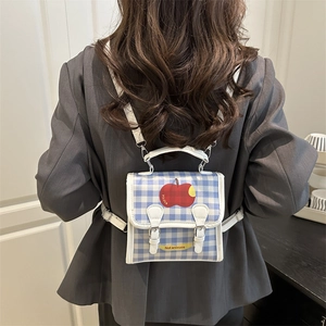 Mini sac à dos à carreaux avec imprimé pomme, porté par un mannequin en bleu