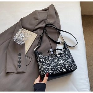 Detail of black and white geometric embroidery pattern on a stylish shoulder bag with strap