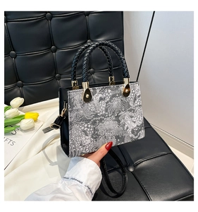 Close-up of luxury floral embroidery handbag with woven handles and gold metal accents