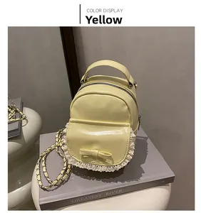 Detail of yellow mini backpack with white lace edges and a bow on a book prop