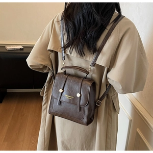 Detail of dark brown leather vintage backpack showing flap cover and gold metal buckles