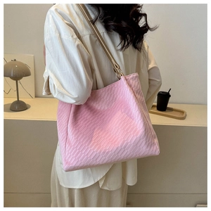 Detail of pink checkerboard tote bag with wide shoulder strap worn by a model