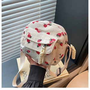 Detailed texture of corduroy fabric featuring red strawberry prints and zipper detail