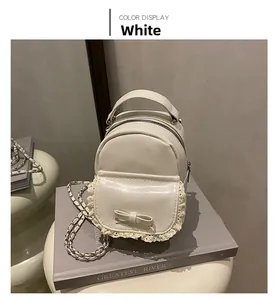 Detail of white mini faux leather backpack with lace trim and bow accent on front pocket