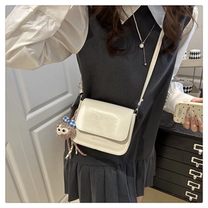 Détail du sac bandoulière en similicuir crème avec gaufrage animal et charm paresseux doux