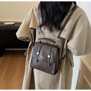 Detail of dark brown vintage backpack with leather texture and metal buckles on a model