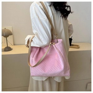 Detail of pink woven tote bag with slim tan leather straps in a minimalist setting