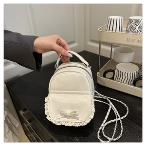 Nahaufnahme des weißen Mini-Rucksacks mit Spitzenbesatz, Schleife und Metallkette