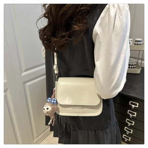 Détail du petit sac bandoulière beige avec motif dessin animé et breloque ours